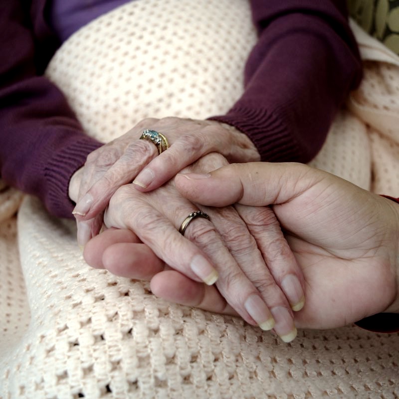 Old lady holdig hands with a younger woman